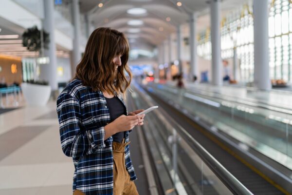 donna-che-cammina-attraverso-l-aeroporto-utilizzando-il-suo-dispositivo-smartphone_273443-4225.jpg
